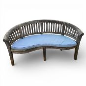 A weathered teak shaped back garden seat with fitted cushion and maker's label. H.85 W.160cm.