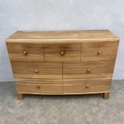 A contemporary bowfronted teak chest in a natural finish. H.89 W.130 D.48cm.