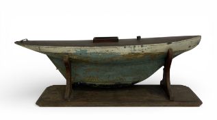 A large C.1900 painted and distressed model pond yacht hull on stand. H.43 W.115cm