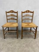 A pair of contemporary 19th century style elm ladder back chairs with rush woven seats on turned