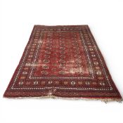 A Bokhara carpet with repeated gul medallions on a burgundy field within stylised flowerhead