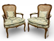 A pair of 19th century French carved beech framed fauteuil armchairs with cane backs over the shaped