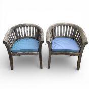 A pair of weathered teak garden tub armchairs with fitted cushion and maker's label. H.84 W.76cm.