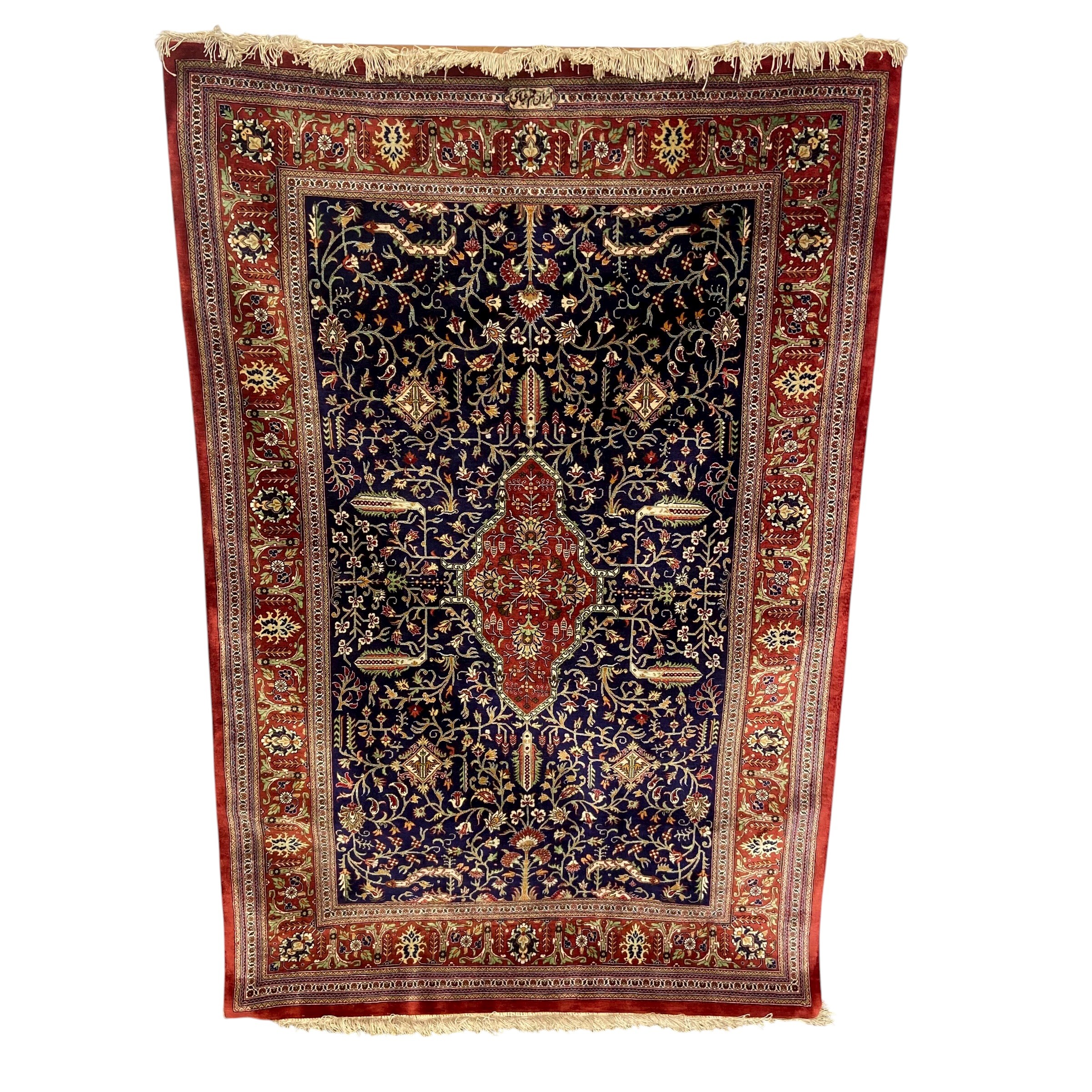 A signed Persian silk Qum rug with central lozenge medallion in a scrolling field over the