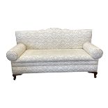 A vintage two seater sofa with shaped back and scrolled arms over the re-upholstered printed