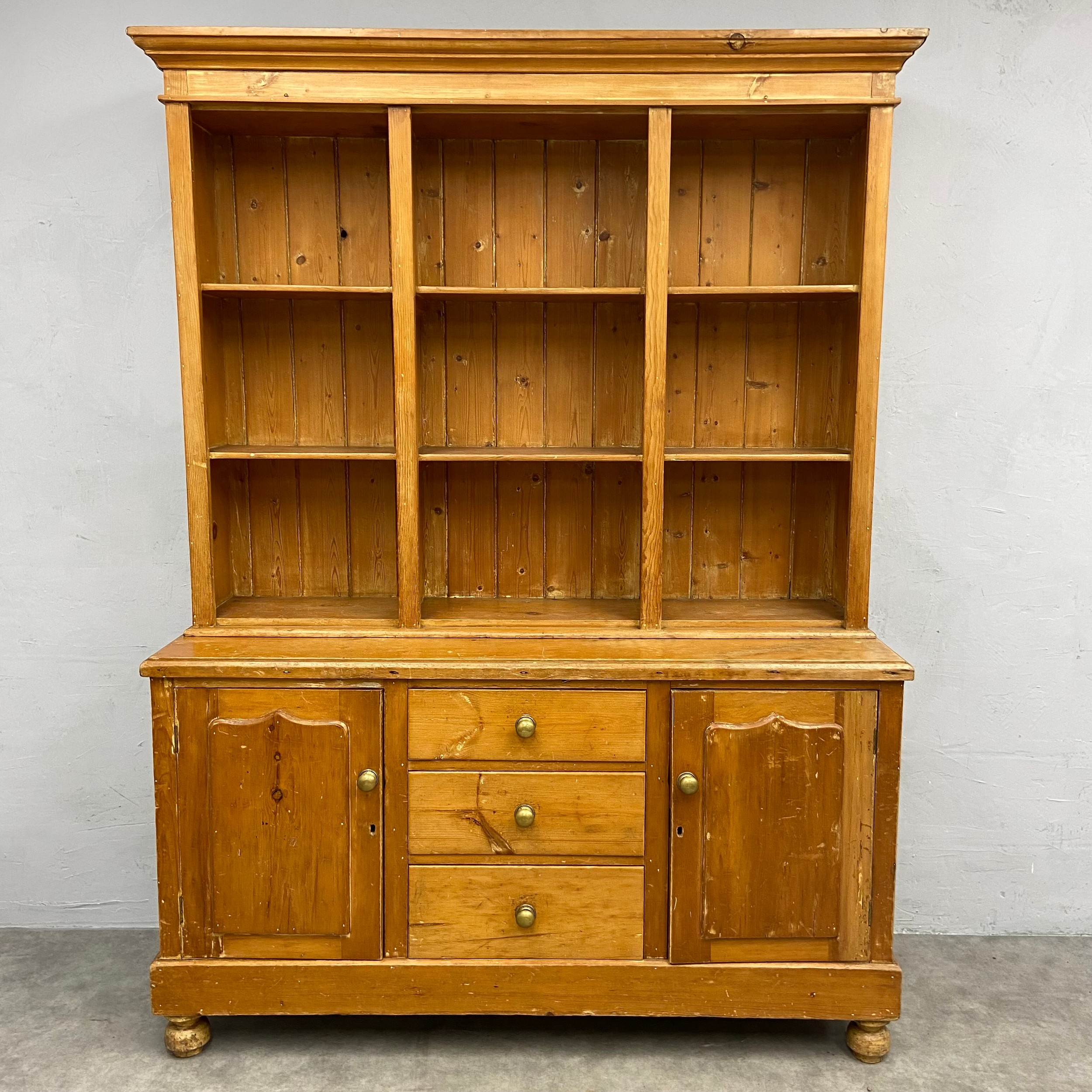 A C.1900 pine dresser in two parts with three shelves over base cabinets and drawers raised on bun
