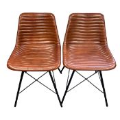 A pair of contemporary retro styled dining chairs with ribbed faux tan leather seats raised on