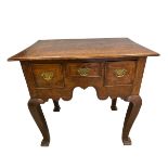 A Georgian oak lowboy with plank top over three frieze drawers raised on square section cabriole