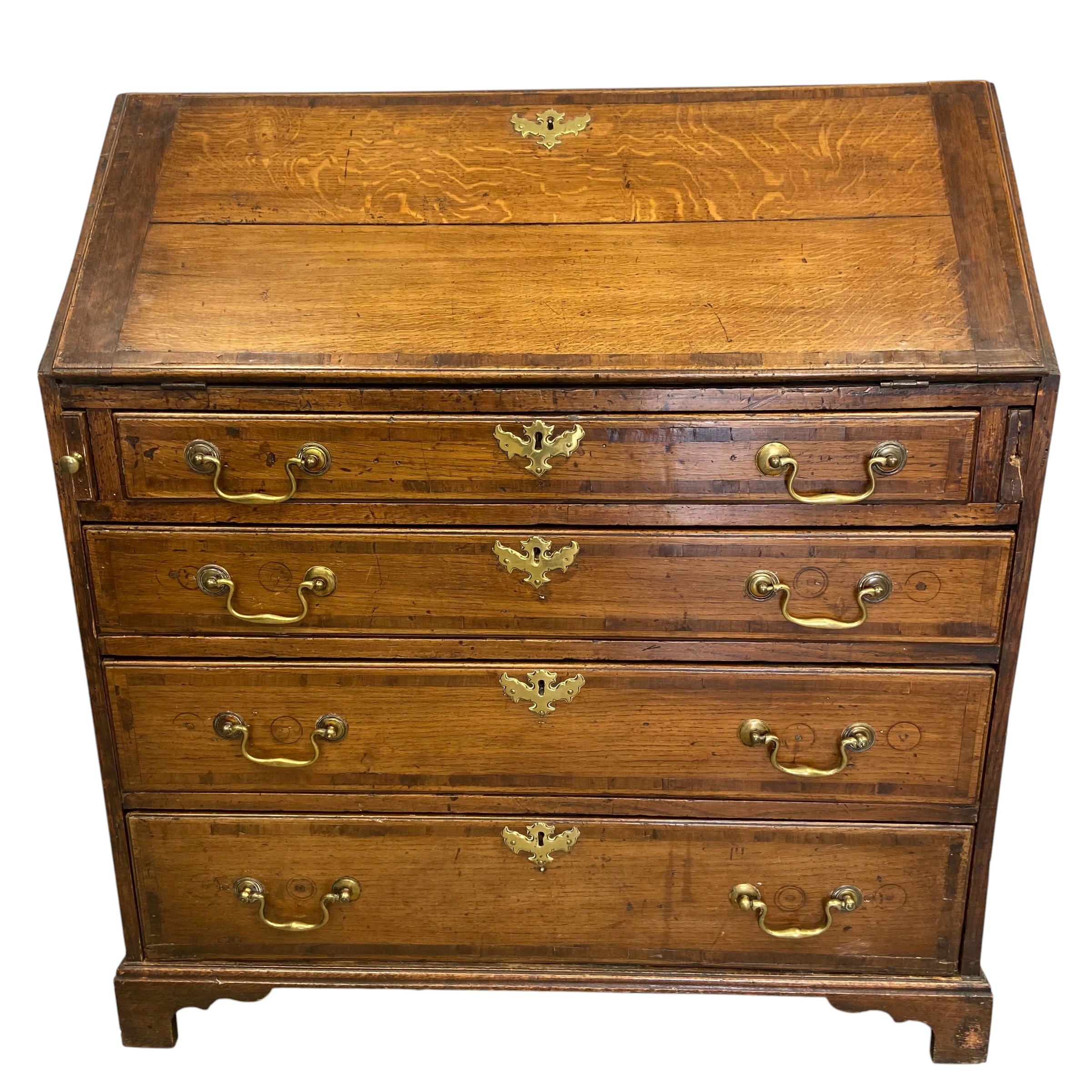 A Georgian oak bureau with fall front enclosing fitted interior over four long graduating drawers