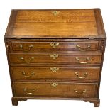 A Georgian oak bureau with fall front enclosing fitted interior over four long graduating drawers