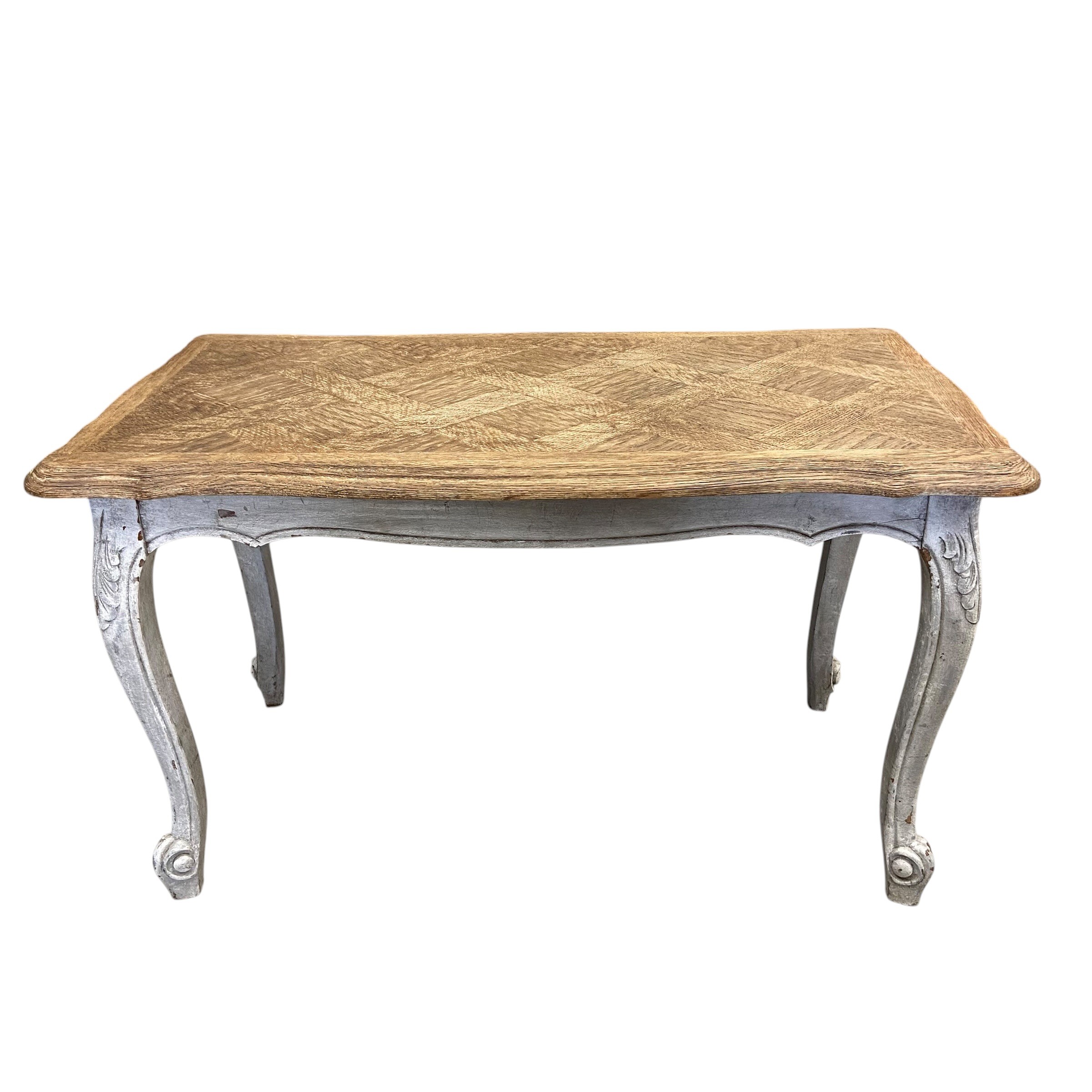 A vintage French farmhouse style coffee table with quatrefoil parquetry top raised on carved,