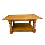 A vintage farmhouse style oak coffee table with plank top raised on heavy turned supports united