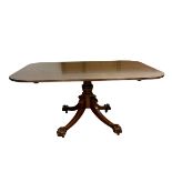 A 19th century mahogany dining table with shaped top over the turned pedestal raised on splayed