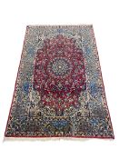 A Persian Najafabad rug with central flowerhead medallion in the polychrome field over a burgundy