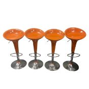 A set of four retro styled bar stools with moulded orange plastic height adjustable seats raised