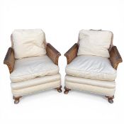 A pair of 19th century mahogany bergere armchairs each having a caned back and scrolled arms with