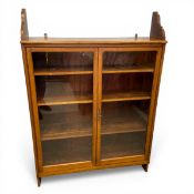 A arge Edwardian walnut wall hanging bookcase with shaped open shelf over the pair of glazed cabinet
