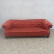 A Victorian three seater Chesterfield sofa with scrolled deep-buttoned back and arms over the red
