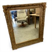 A large 19th century wall mirror with matched bevelled plate in a scrolling gilt gesso frame.