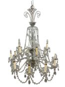 A large vintage cut glass chandelier with four scrolled tendrils over the baluster form stem and