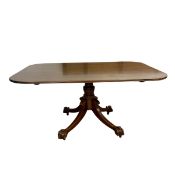 A 19th century mahogany dining table with shaped top over the turned pedestal raised on splayed