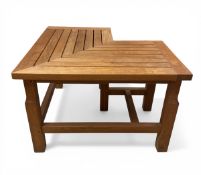 A vintage style teak garden corner bench with slatted seat raised on stretchered supports by