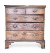 A Georgian oak chest of two short over three long graduating drawers raised on shaped bracket