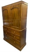 A mid 19th century mahogany two section linen press with shaped and figured panel doors enclosing