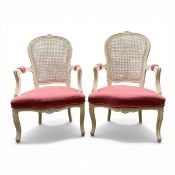 A pair of 20th century French style bergere fauteuil armchairs with carved crestings over the cane