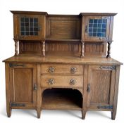 A C.1900 oak Arts & Crafts sideboard having a break-fronted superstructure with leaded glass