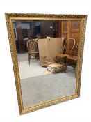 A vintage wall mirror with rectangular bevelled plate in a scrolling gilt frame. 100x129cm.