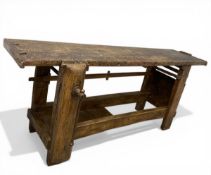 A 19th century French pine artisans work bench having a distressed plank top over heavy