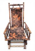 An Edwardian beech rocking chair with floral velour upholstery over a turned frame raised on