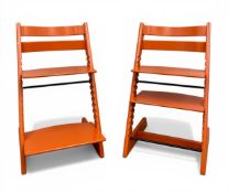 A vintage Norwegian pair of child's adjustable 'Tripp Trapp' high chairs with a lacquered orange