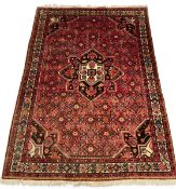 A Persian Hosseinabad carpet with central flowerhead medallion in a patterned polychrome field