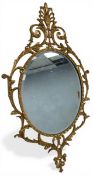 A mid 20th century brass wall mirror with oval bevelled plate in scrolling foliate openwork frame.