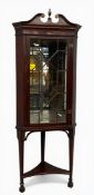 An Edwardian mahogany floor-standing corner display cabinet having a swan-neck pediment with urn