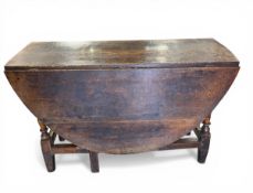 A Georgian oak drop-leaf table with circular plank top over the shaped apron raised on turned and