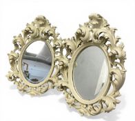 A pair of vintage Florentine style composite moulded wall mirrors with oval bevelled plates in