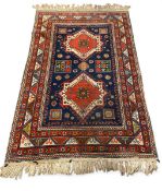 A Caucasian style Kazak carpet with two diamond lozenge medallions over the midnight blue ground