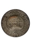 A large moulded and bronzed ceramic charger depicting 'The Entry of the Victors' after the relief of