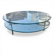 A contemporary two-tier coffee table with circular plate glass top and undertier raised on