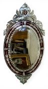A large vintage Venetian style wall mirror with scrolling foliate cresting over the oval bevelled