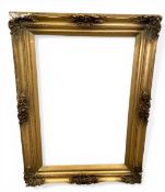 A large C.1900 gilt gesso picture frame of simple shaped form with scrolling foliate crestings and