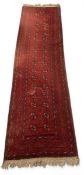 A Bokhara runner with repeating gul medallions on a burgundy field within multiple geometric
