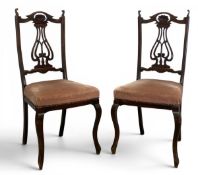 A pair of Art Nouveau style beech dining chairs each with shaped back and stylised openwork tulip