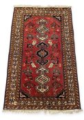 A Persian style Shiraz rug with central geometric pole medallion over the iron red ground within