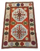 A Turkish Kazak Kars rug with two stepped lozenge medallions over a box red ground within a