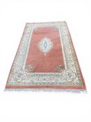 A contemporary Chinese style carpet with central scrolling foliate medallion over a pale pink ground