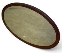An Edwardian mahogany wall mirror with oval bevelled plate in a simple inlaid frame. H.63 W.88cm